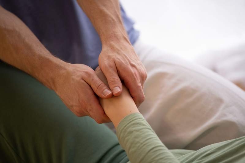 Hands holding receivers hand in contact, in a thai massage session